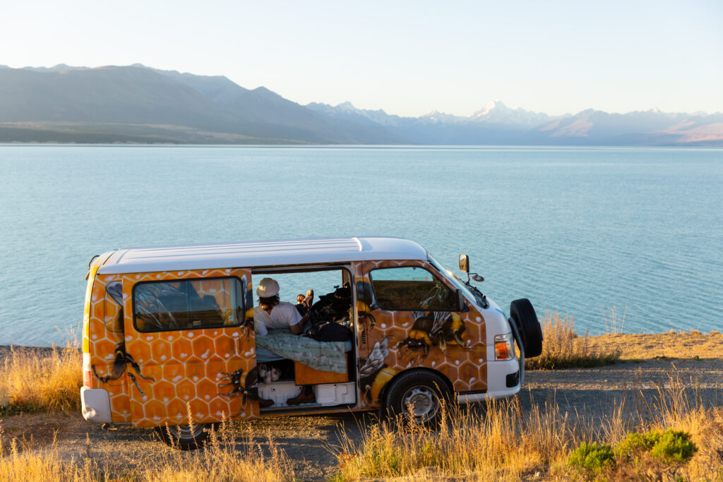 Person sitting in campervan with lake scenery